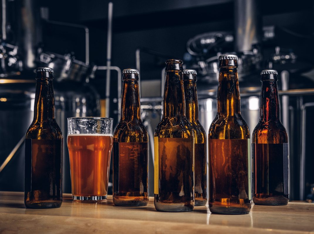 bottles-and-glass-of-craft-beer-on-wooden-bar-counter-at-the-indie-brewery-.jpg